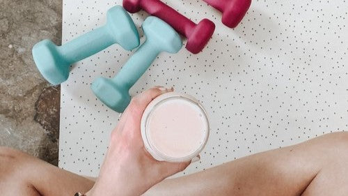 cross legged figure holding drink with dumbbells in front of them