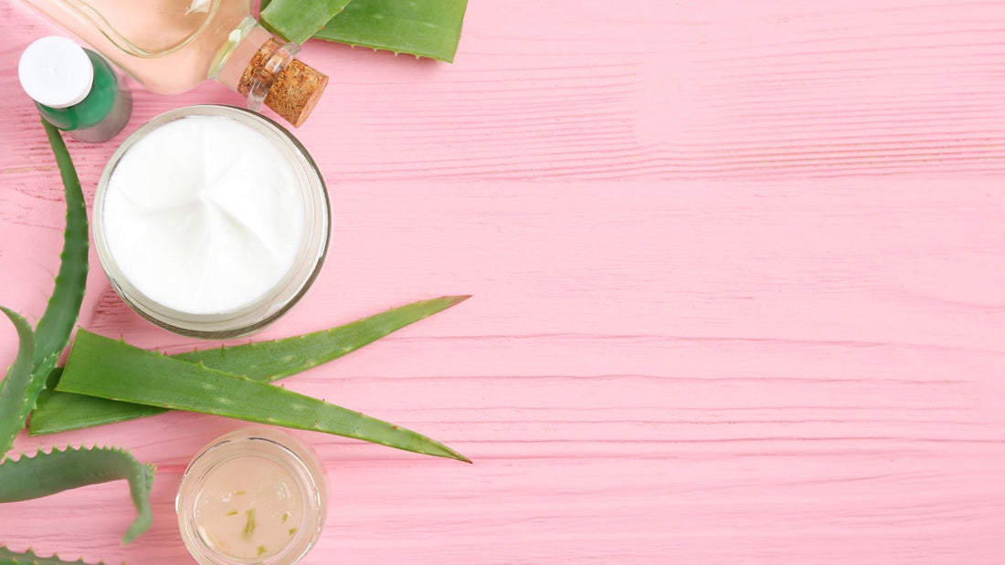 aloe vera leaves and a bowl of lotion on a pink background