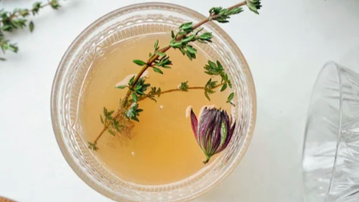 herbal tea in glass with herbs and petals floating on top