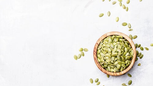 Small bowl of pumpkin seeds white background. 