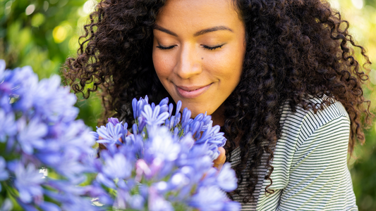 Close up of a smiling woman smelling the scent of flowers