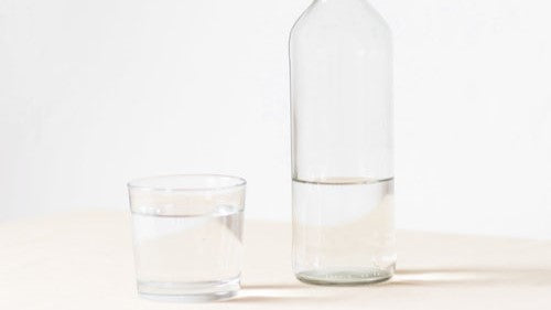 clear glass and bottle of water on white background