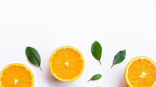 Vibrant orange slices and green leaves on white background