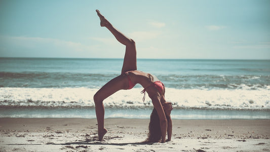 Slender woman in bikini doing a yoga pose in front of the sea