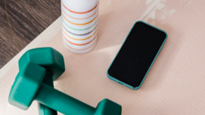 Dumbbells, phone and water bottle on a pink table