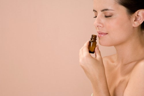 woman breathing in the scent from a bottle of essential oil 